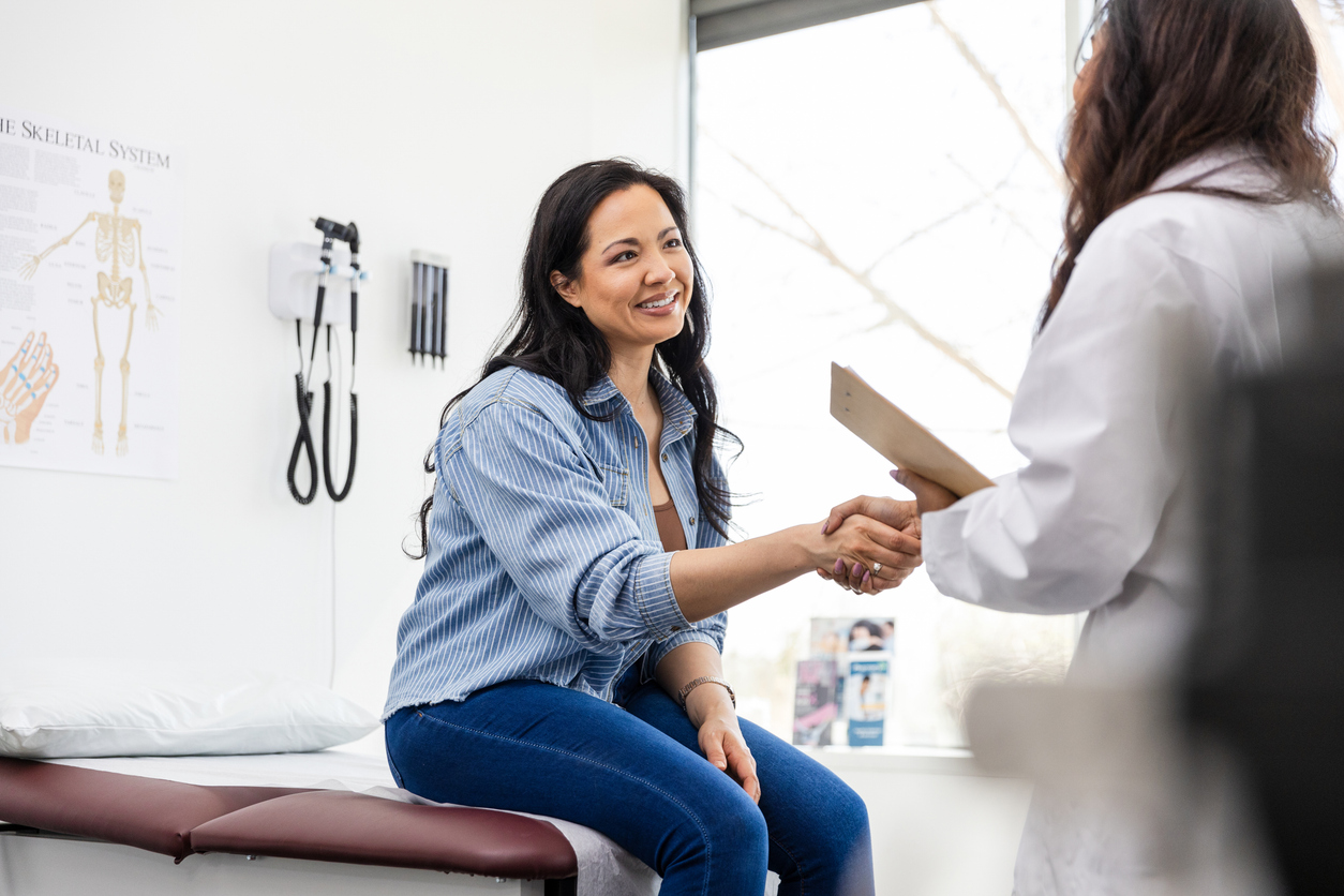 Mid adult female patient shakes hands with her doctor female patient shaking hands with female doctor in exam room